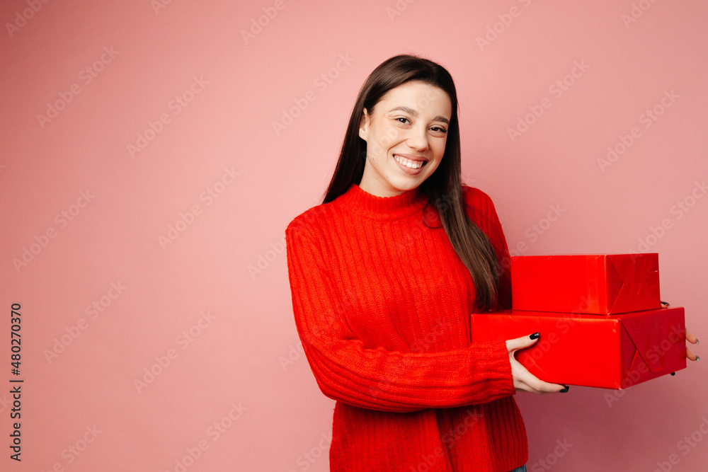 The girl is smiling and showing her presents in the red package. Concept of the St. Valentine's Day The girl is smiling and showing her presents in the red package. Concept of the St. Valentine's Day