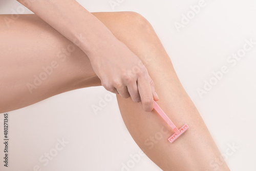 young woman leg with razor in hand shaving removing hair. body care depilation