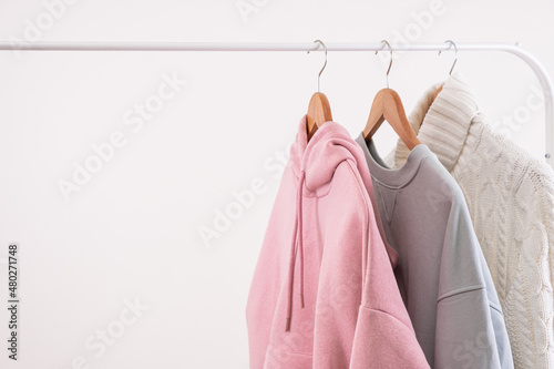 Pastel colors casual female clothes on wooden hangers on open rail copy space