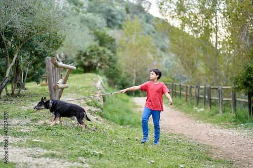 Cute little boy  walking his little pet dog in rural rapeseed field next to him  boy walking on a small path