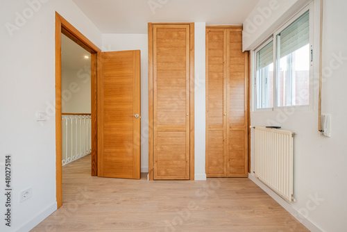Bedroom with cherry-colored fitted wardrobes and Venetian doors and white aluminum radiator
