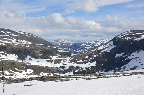 Clouds and blue sky over the rocka and snow in a mountain valley in Norway, Northern Europe