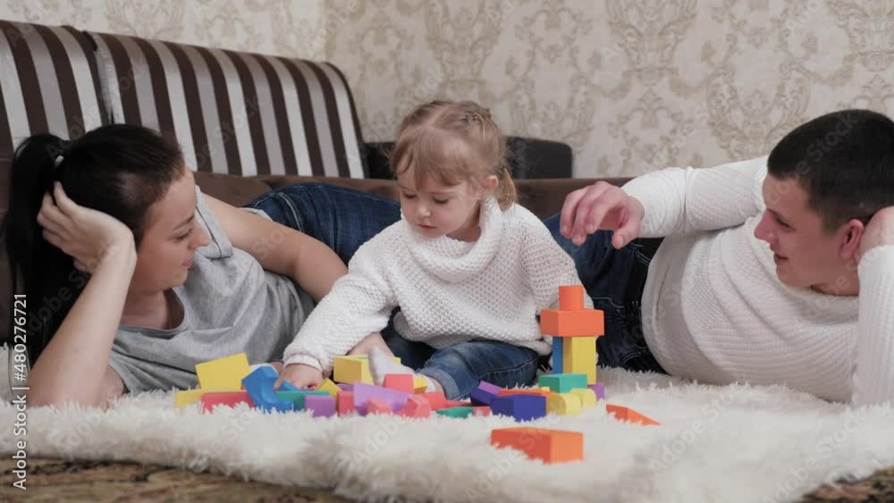 Happy adult parents dad, mom help cute preschool daughter play toys on ...