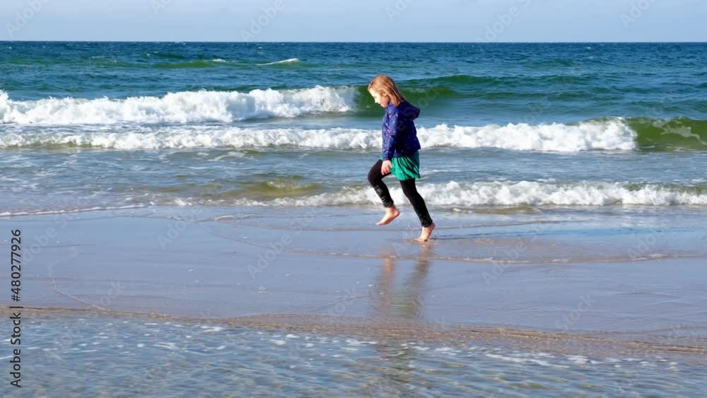 Young Happy Caucasian Girl in Green Skirt Running Barefoot Along Beach at Seashore on Sunny Windy Day Young Happy Caucasian Girl in Green Skirt Running Barefoot Along Beach at Seashore on Sunny Windy Day