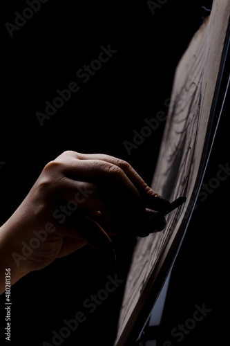 Artist drawing with chalk. Abstract hand painting on paper against black background.