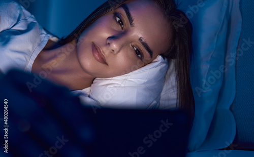 Woman using smartphone in bed with before sleep