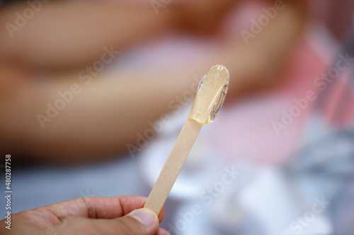 Sugaring wax used for hair removal is applied to the tip of the wooden stick.