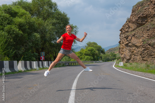 young woman jumping along the middle of the road
