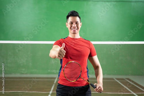 Smiling male badminton player holding racket with thumbs up © Odua Images