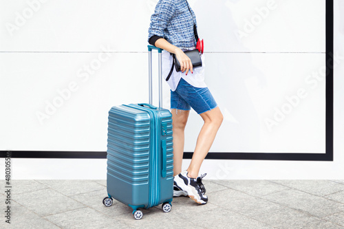 Female traveler walking with blue suitcase on the street city