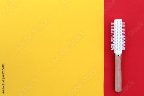 A white hair styling brush lies on a bright background.