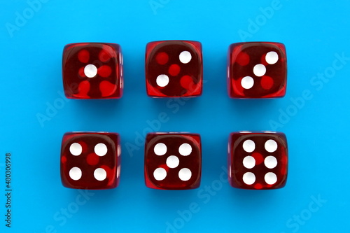 Six red dice lie on an isolated blue background.