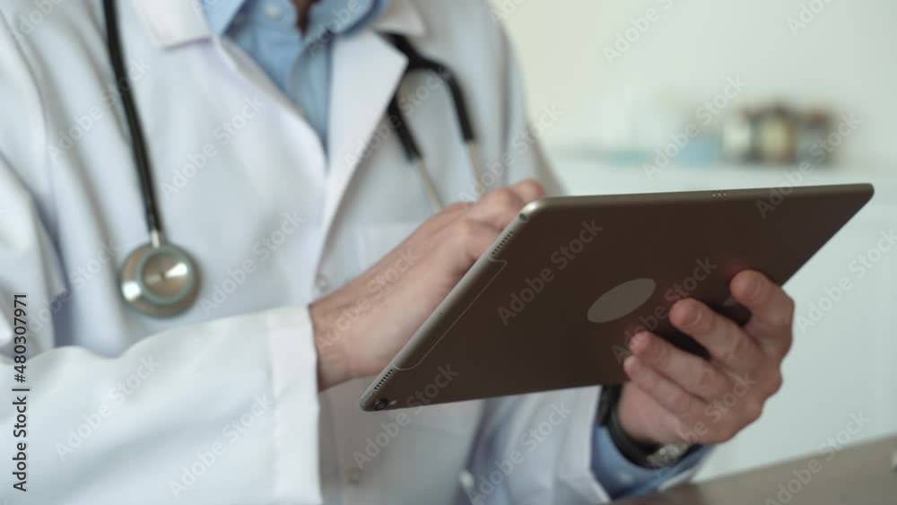 Close up view of male doctor hands using healthcare software application on tablet. Social network. Telemedicine, Remote. Healthcare services in pandemic concept. No face. 4k footage Close up view of male doctor hands using healthcare software application on tablet. Social network. Telemedicine, Remote. Healthcare services in pandemic concept. No face. 4k footage