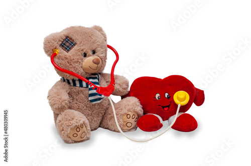 A teddy bear listens to a toy heart with a fanendoscope. Provision of medical care. Isolated children's toys on a white background. photo