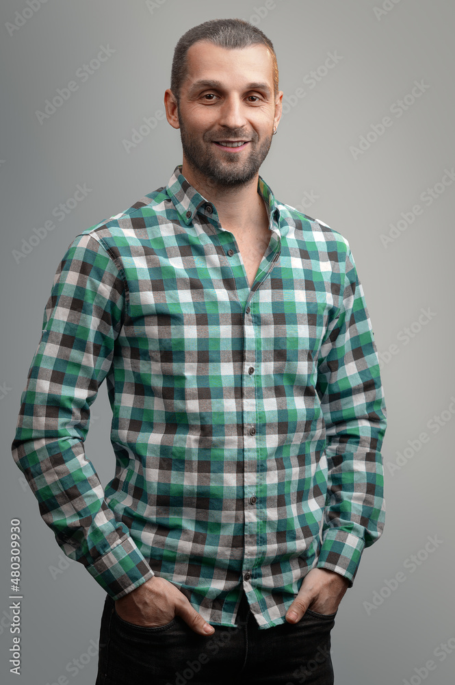 Portrait of a smiling man in a green plaid shirt on a gray background. Portrait of a smiling man in a green plaid shirt on a gray background.