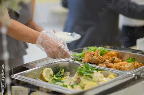 a person wearing gloves scooping food, catering, dinner time, prevent Coronavirus disease (covid 19)