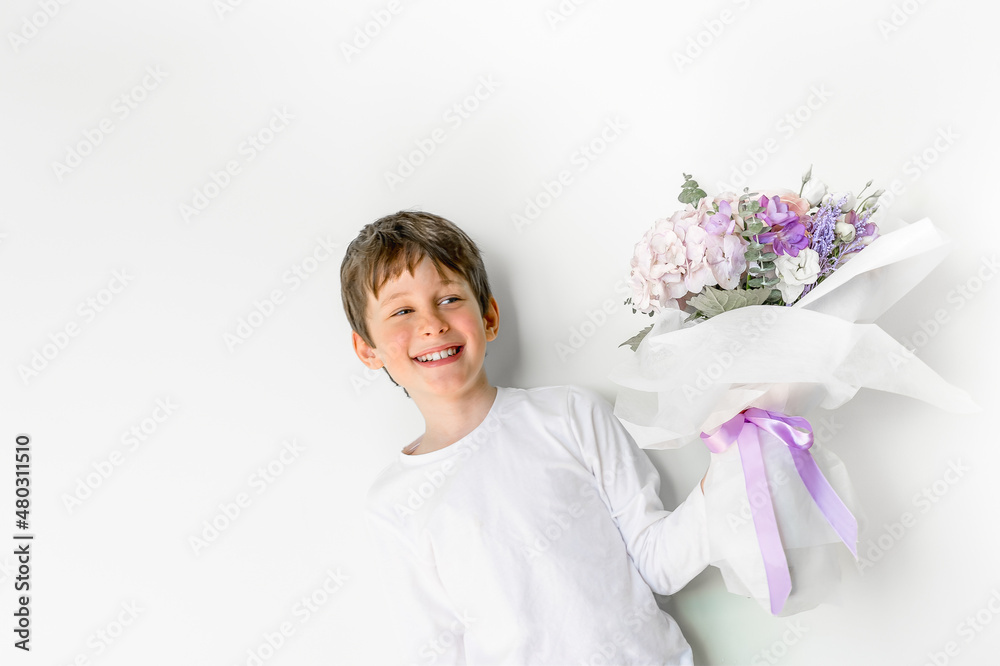 Laughing charming boy with a bouquet of flowers in his hands smiles. Greeting card mockup with copy space. Portrait of a boy 8 years old, white, caucasian Laughing charming boy with a bouquet of flowers in his hands smiles. Greeting card mockup with copy space. Portrait of a boy 8 years old, white, caucasian