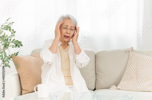 部屋にいる高齢者女性（悩む・頭痛）  © buritora