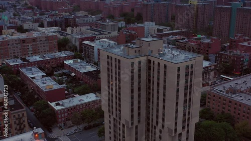 Dramatic aerial diagonal tilt up across Harlem New York City rooftops revealing the Harlem skyline at sunset blue hour photo