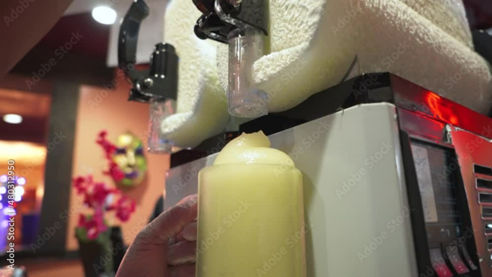 Bartender pours frozen margarita from machine into frosted mug, slow motion 4K