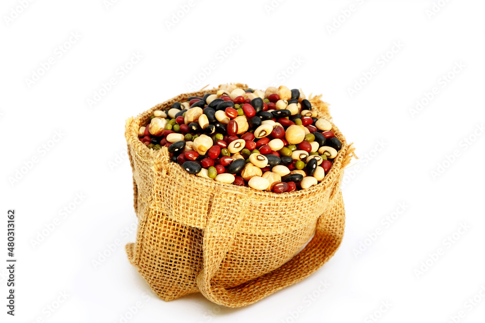 Close up mixed five color of organic bean dry raw food high protein green red black  beans soybean chickpeas in brown hemp sack bag natural light isolated on white 