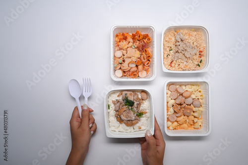 Woman holding spoon and fork ready to microwave and eat several frozen meal.