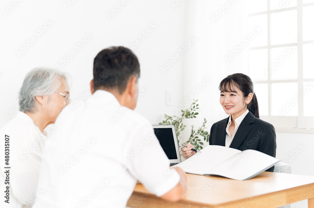 資料で説明するスーツ姿の女性と高齢者夫婦
資料で説明するスーツ姿の女性と高齢者夫婦