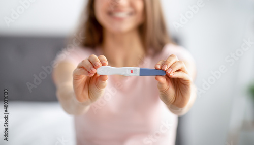 Unrecognizable young woman showing positive pregnancy test  feeling happy over future baby at home  selective focus
