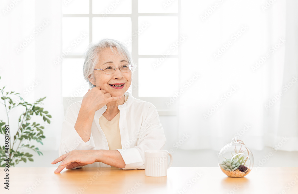 窓辺に座る高齢者女性(笑顔)
窓辺に座る高齢者女性(笑顔)