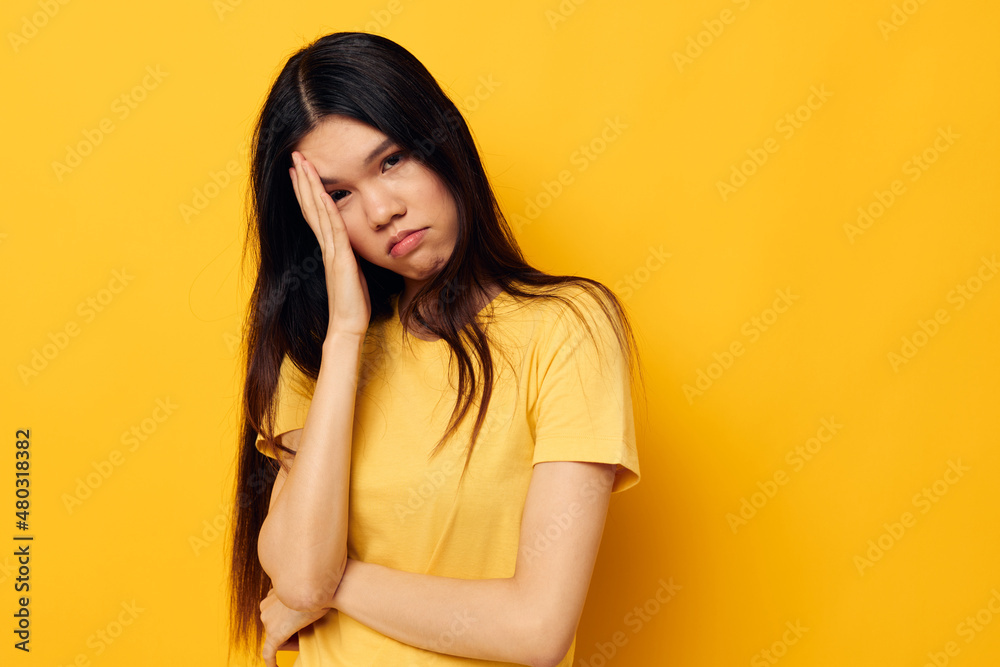 woman in a yellow t-shirt holding his head discontent studio model unaltered woman in a yellow t-shirt holding his head discontent studio model unaltered