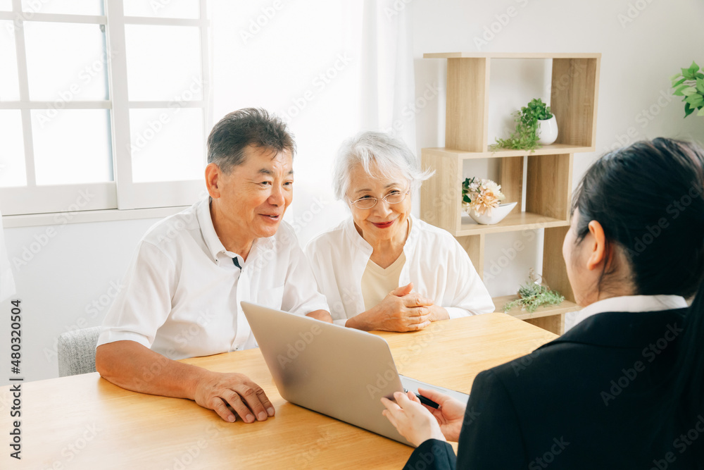 Obraz premium パソコンで説明するスーツ姿の女性と高齢者夫婦 
