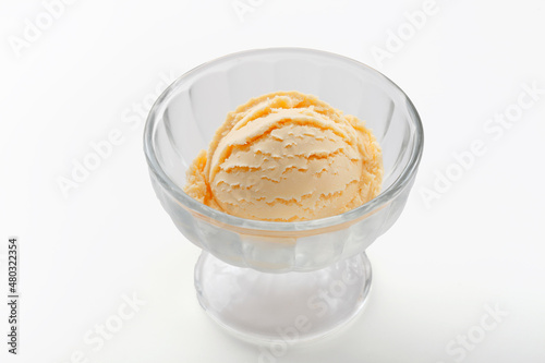 One scoop of vanilla ice cream in glass cup on white background