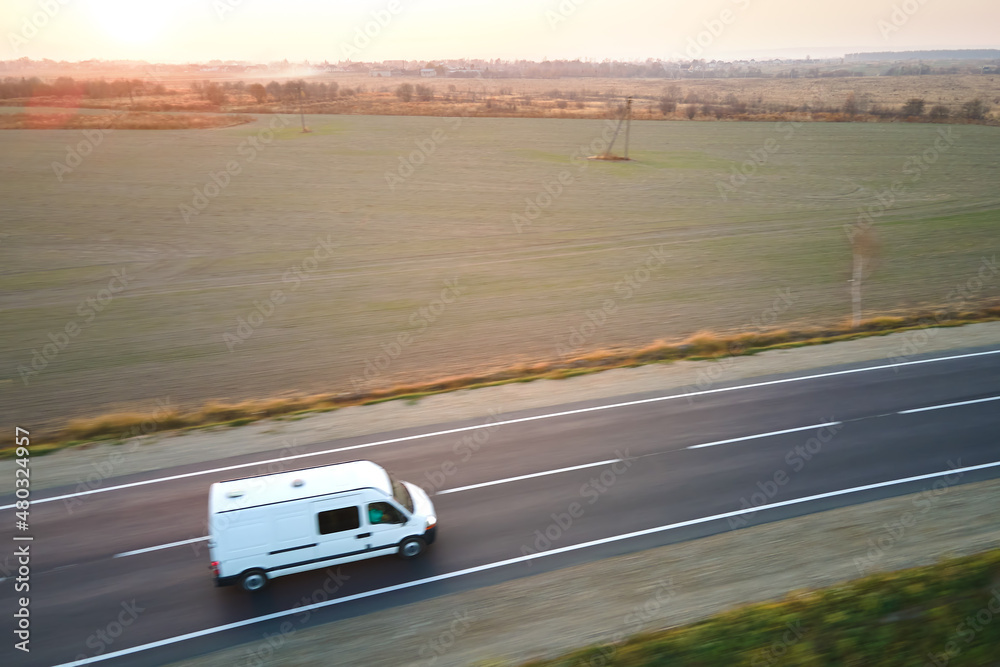 Aerial view of blurred fast moving cargo van driving on highway hauling goods. Delivery transportation and logistics concept Aerial view of blurred fast moving cargo van driving on highway hauling goods. Delivery transportation and logistics concept