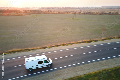 Aerial view of blurred fast moving cargo van driving on highway hauling goods. Delivery transportation and logistics concept © bilanol