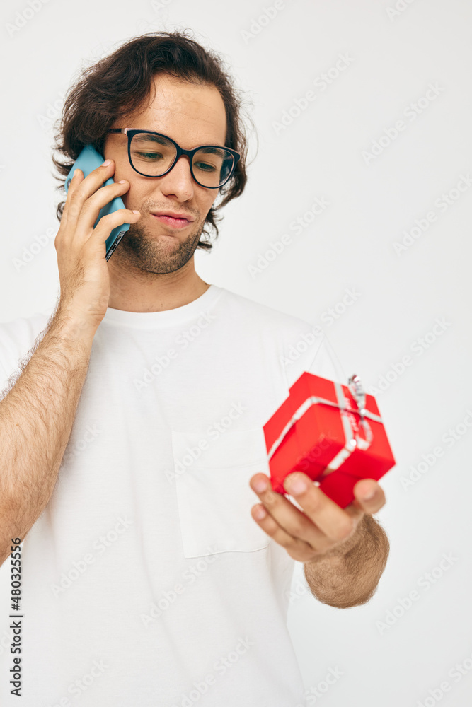 Cheerful man Red gift box telephone communication light background Cheerful man Red gift box telephone communication light background