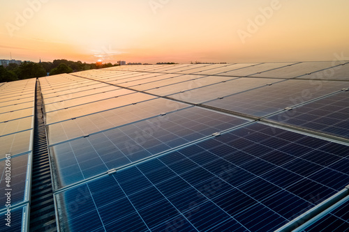 Bild auf Leinwand Blue photovoltaic solar panels mounted on building roof for producing clean ecological electricity at sunset