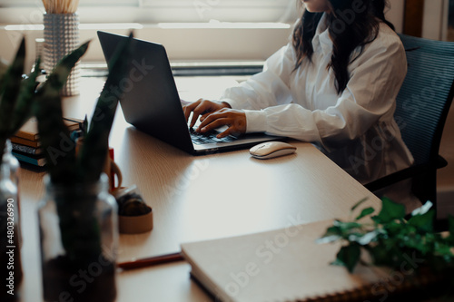 Woman typing at laptop keyboard on desk