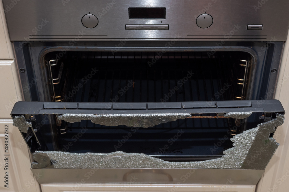 Opened broken oven door in the kitchen, top view, closeup. Broken