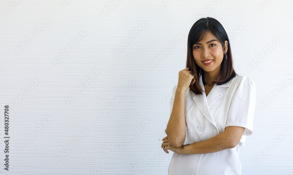 Portrait studio shot of Asian young happy beautiful long hair female businesswoman entrepreneur in white outfit stand crossed arm posing smiling look at camera in front wall background with copyspace Portrait studio shot of Asian young happy beautiful long hair female businesswoman entrepreneur in white outfit stand crossed arm posing smiling look at camera in front wall background with copyspace