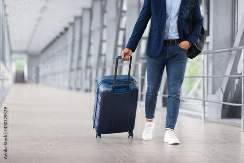 Unrecognizable Man In Casual Clothes Walking With Luggage At Airport Terminal