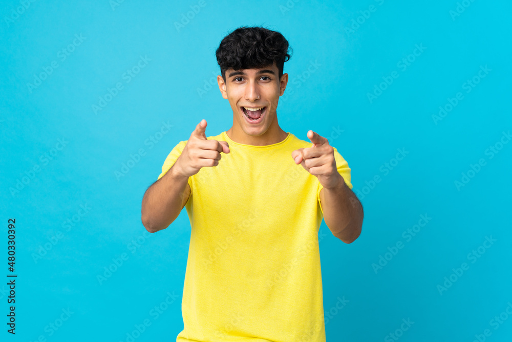 Young Argentinian man isolated on background surprised and pointing front Young Argentinian man isolated on background surprised and pointing front