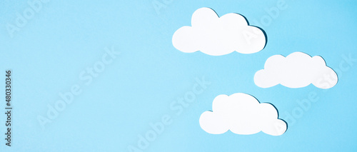 Silhouettes of clouds from white paper on a blue background. Banner, flat lay, place for text.