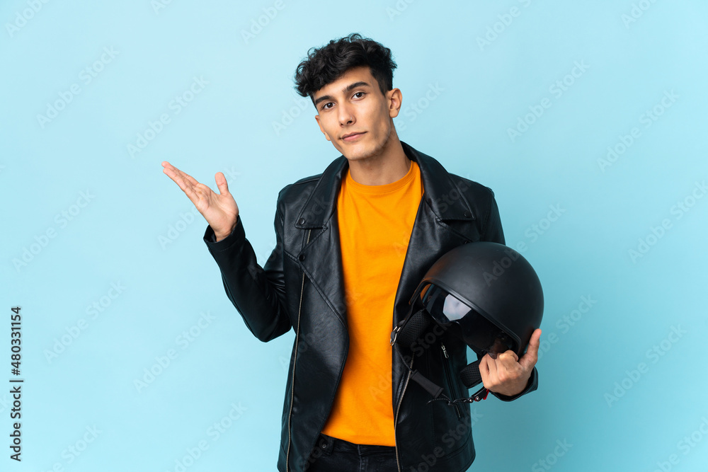 Argentinian man with a motorcycle helmet extending hands to the side for inviting to come Argentinian man with a motorcycle helmet extending hands to the side for inviting to come