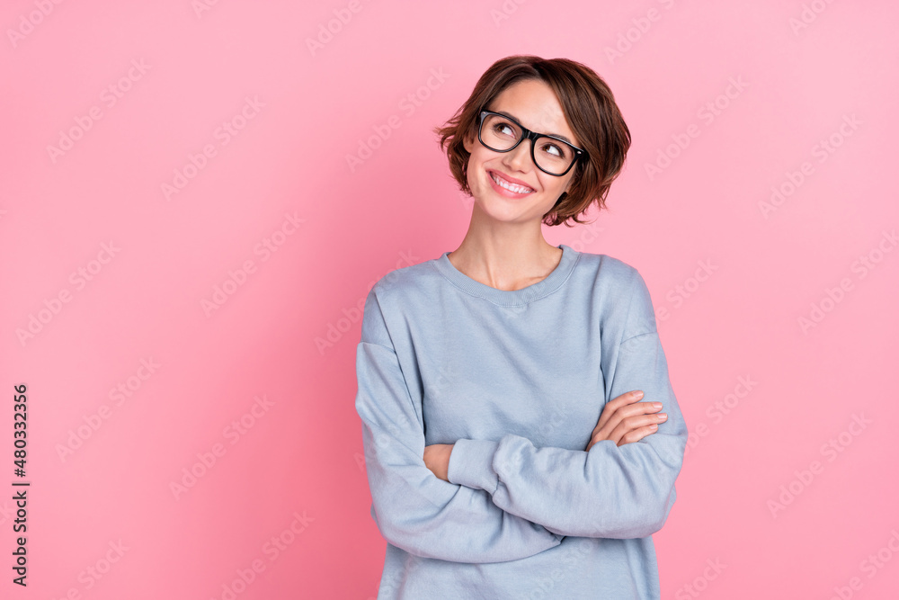 Portrait of attractive cheerful bewildered girl folded arms deciding copy blank space isolated over pink pastel color background