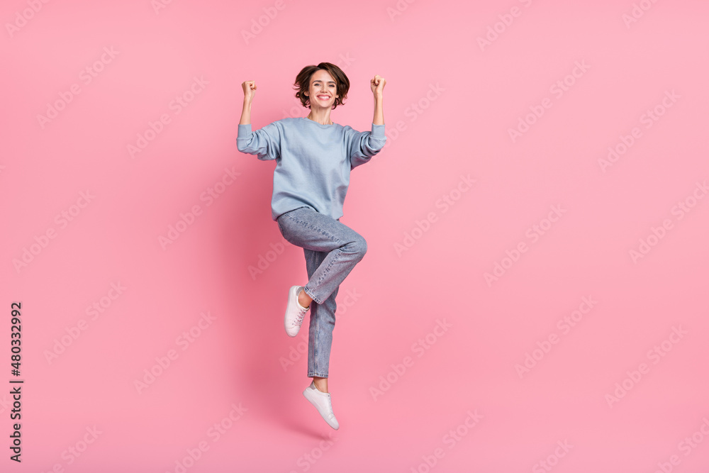 Full body photo of cool millennial lady jump hands fists wear jumper jeans shoes isolated on pink background Full body photo of cool millennial lady jump hands fists wear jumper jeans shoes isolated on pink background
