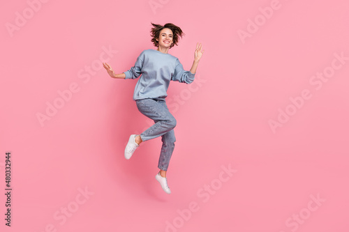 Full length photo of cool millennial lady jump wave wear jumper jeans footwear isolated on pink background