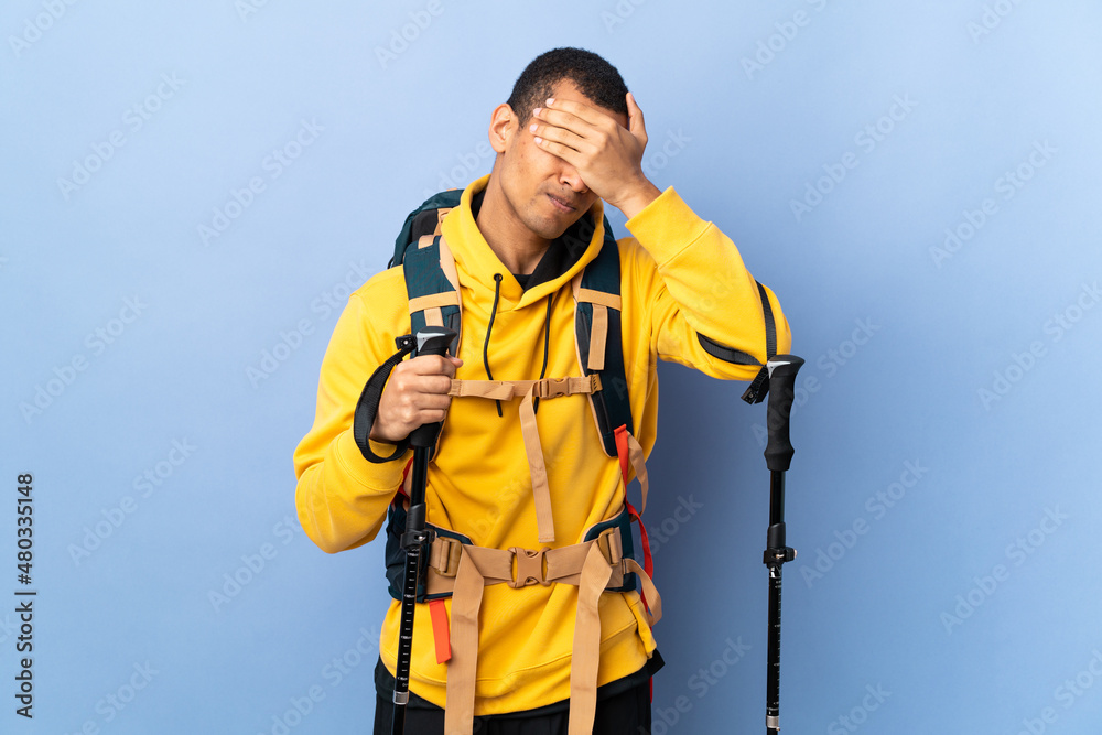 African American man with backpack and trekking poles over isolated background with headache