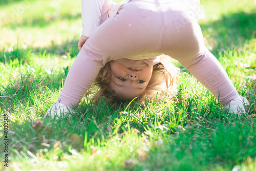 Lifestyle portrait baby girl child in happines at the outside in the meadow upside down.
