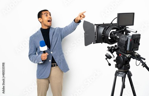 Reporter African American man holding a microphone and reporting news over isolated white background pointing away