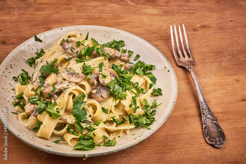 Fettuccine pasta with creamy mushroom sauce and parsley - portion in a plate, close-up